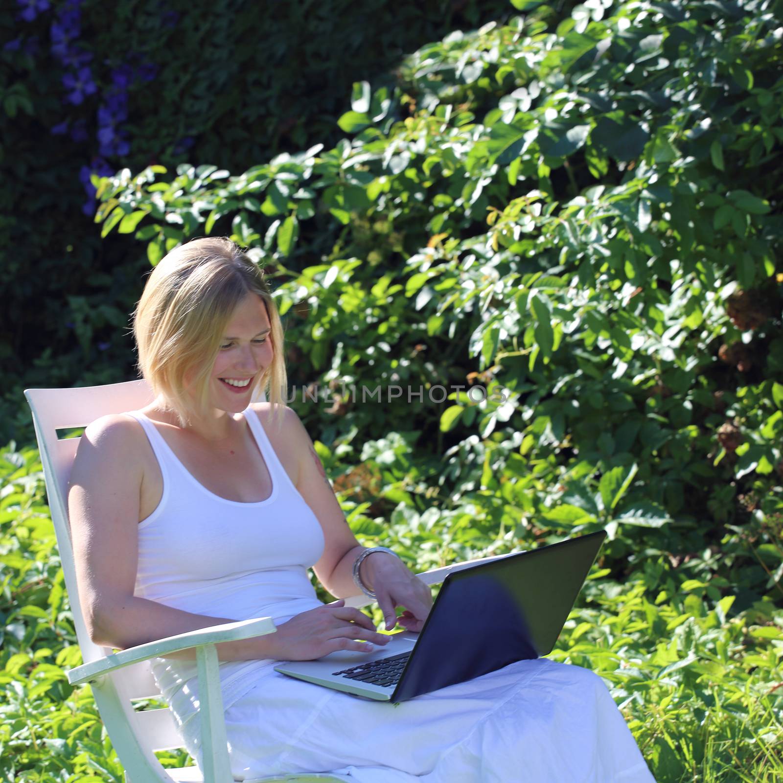 Woman with laptop outdoors by destillat