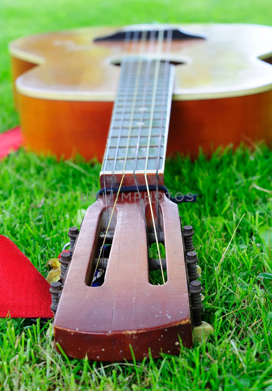 Closeup of old guitar laying on the grass. by hamik