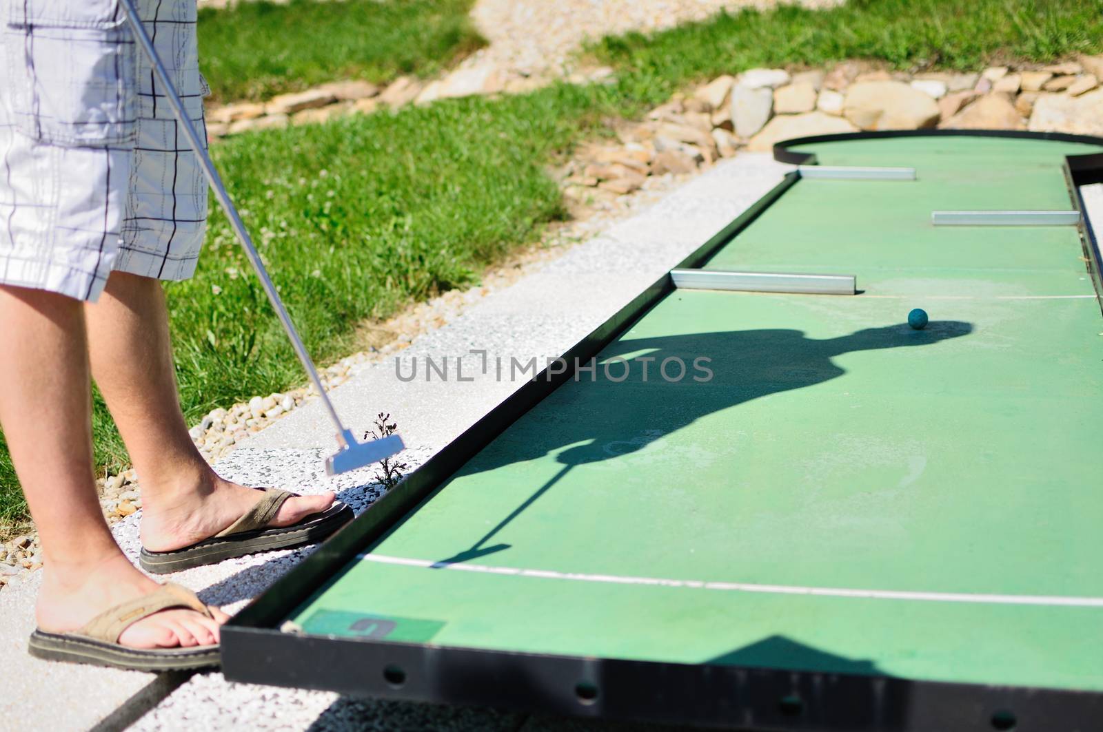 Man in white shorts playing minigolf.