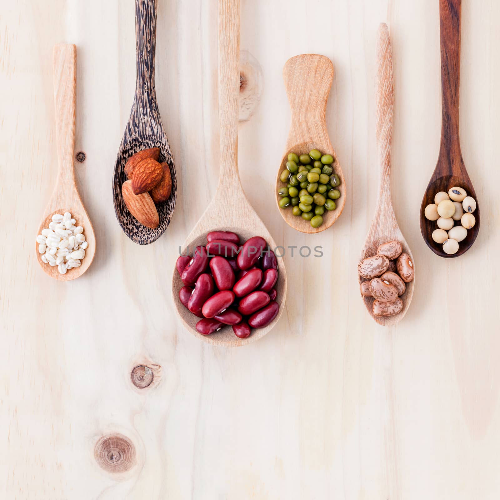 Assortment of beans and lentils in wooden spoon on wooden background. mung bean, groundnut, soybean, red kidney bean and almond.