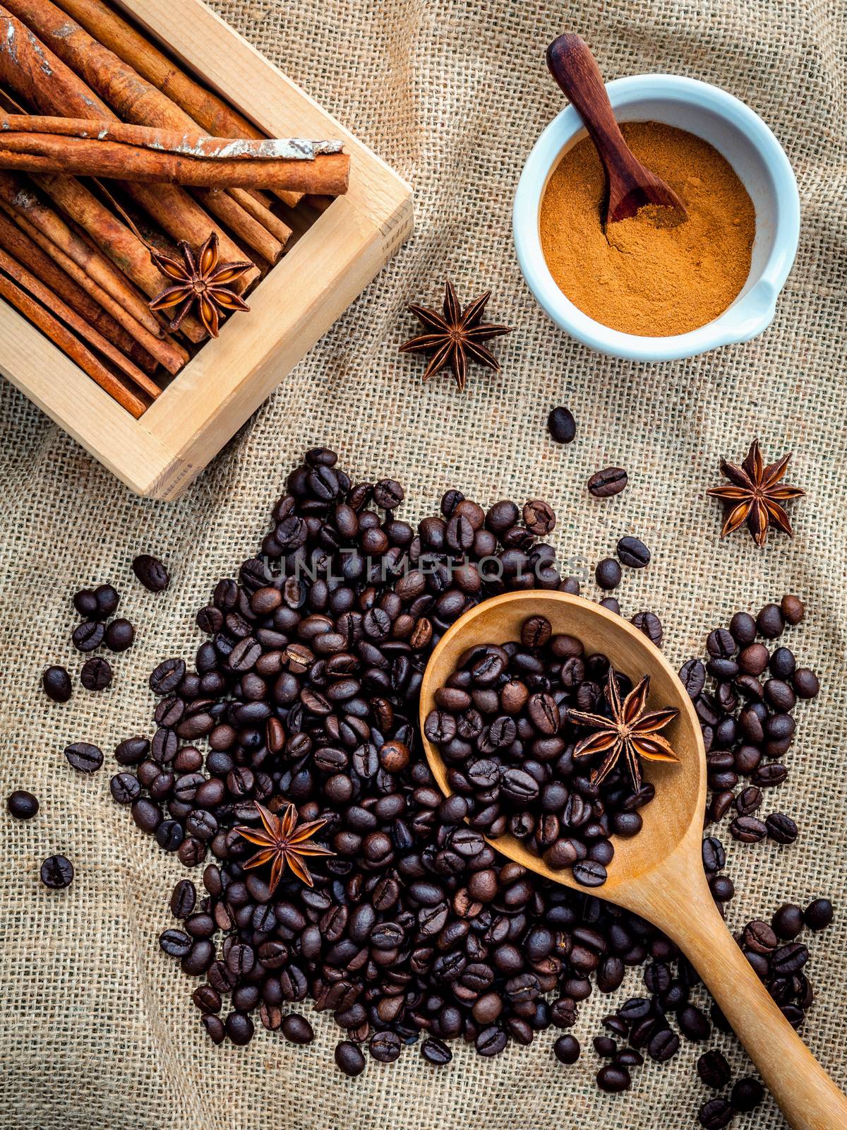 The Cup of coffee beans on the cloth sack with cinnamon sticks ,cinnamon powder in the bowl and star anise.