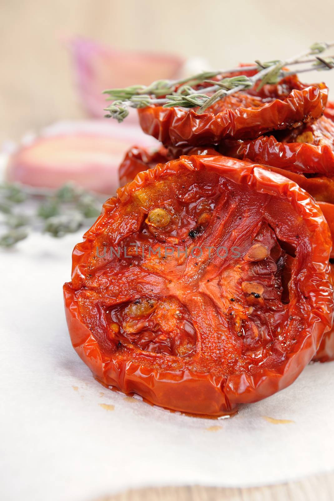 pile of dried tomatoes stacked on a baking paper with cumin and garlic