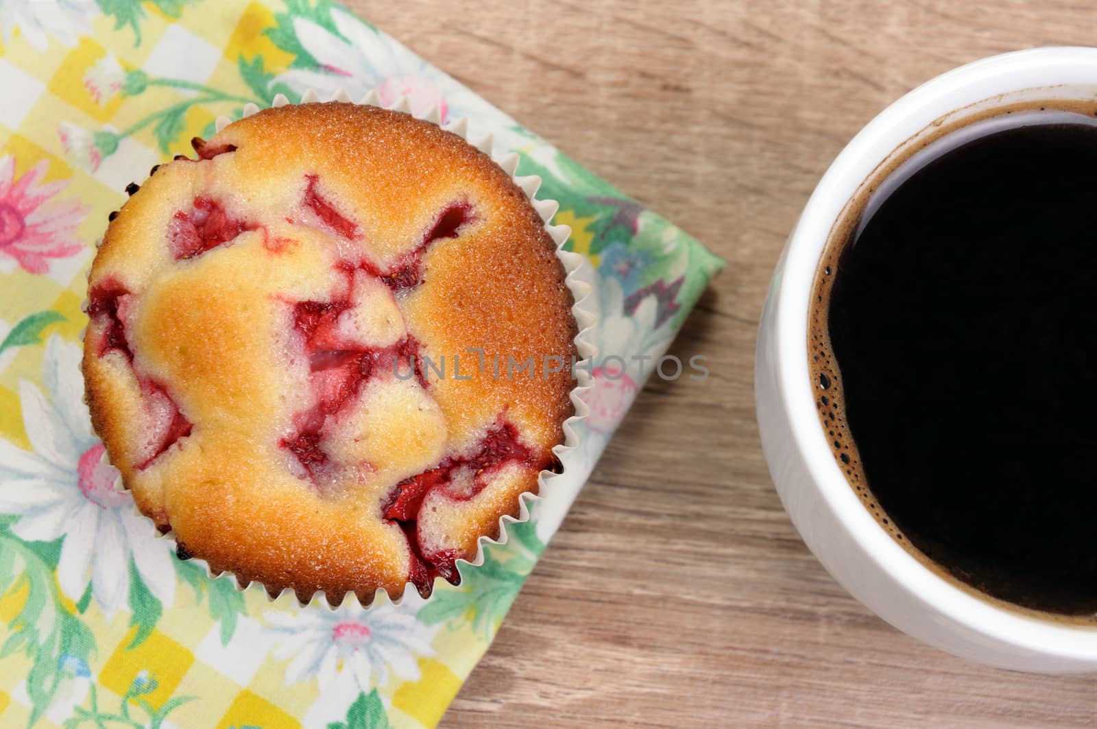 Muffin filled with strawberries on a table  cup of coffee