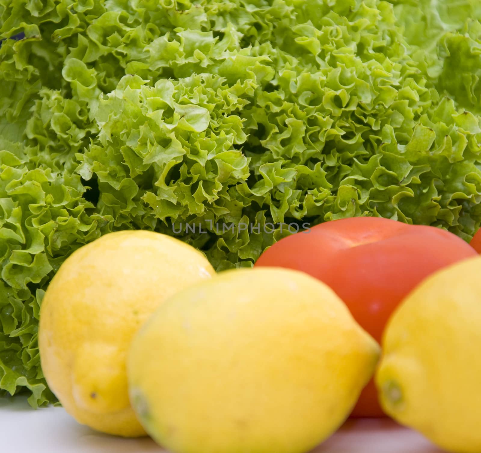 Fresh vegetable salad with lettuce, lemons and tomatoes.