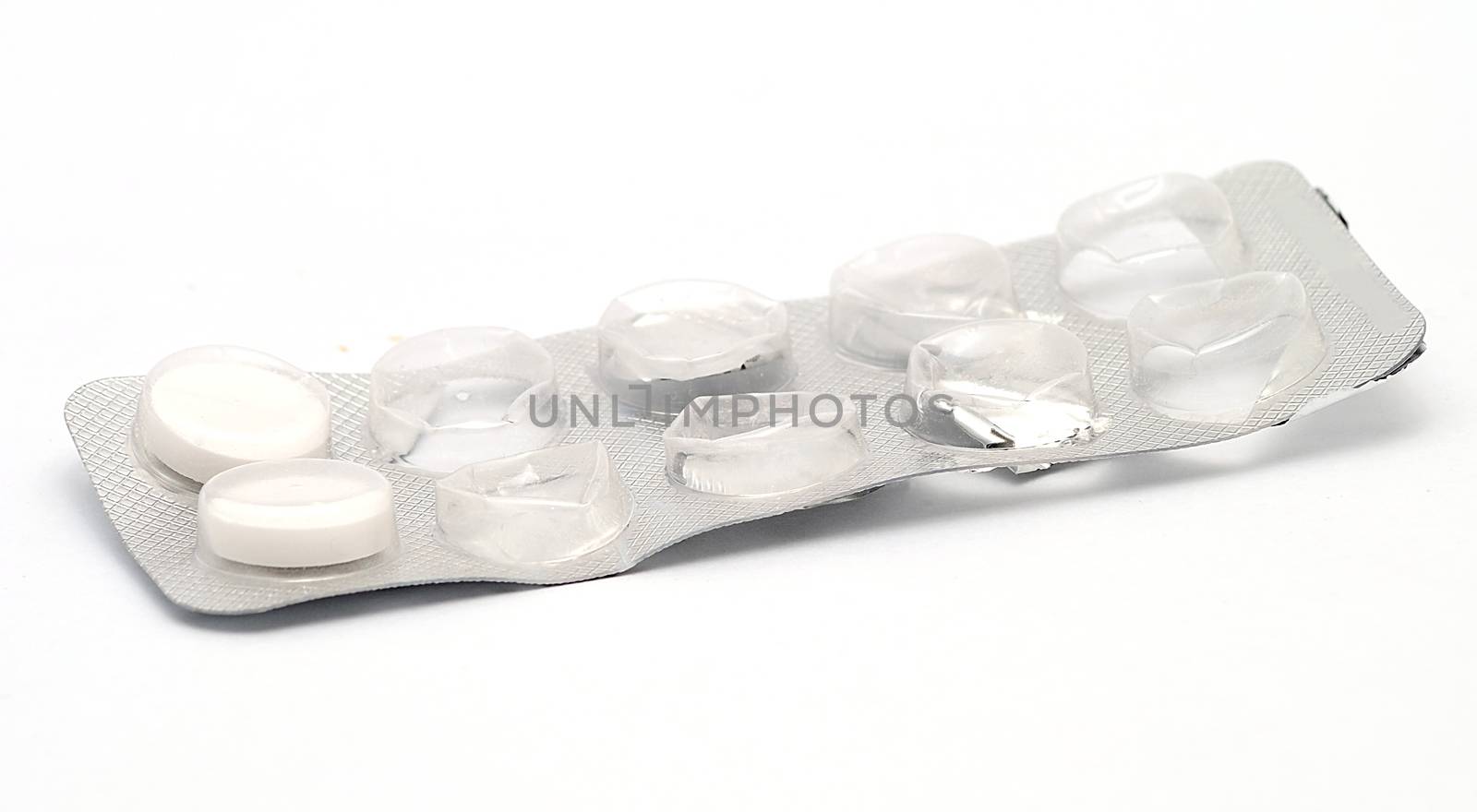 White pills in opened grey box on white background.