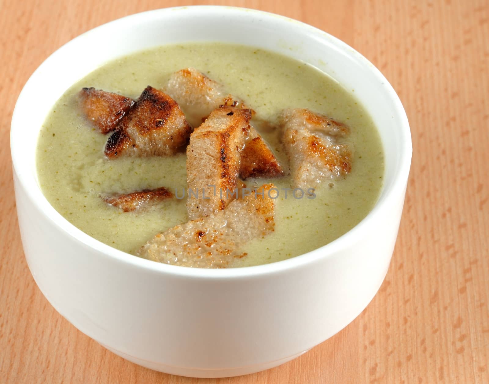 Close-up image of broccoli soup in white dish with crouton.
