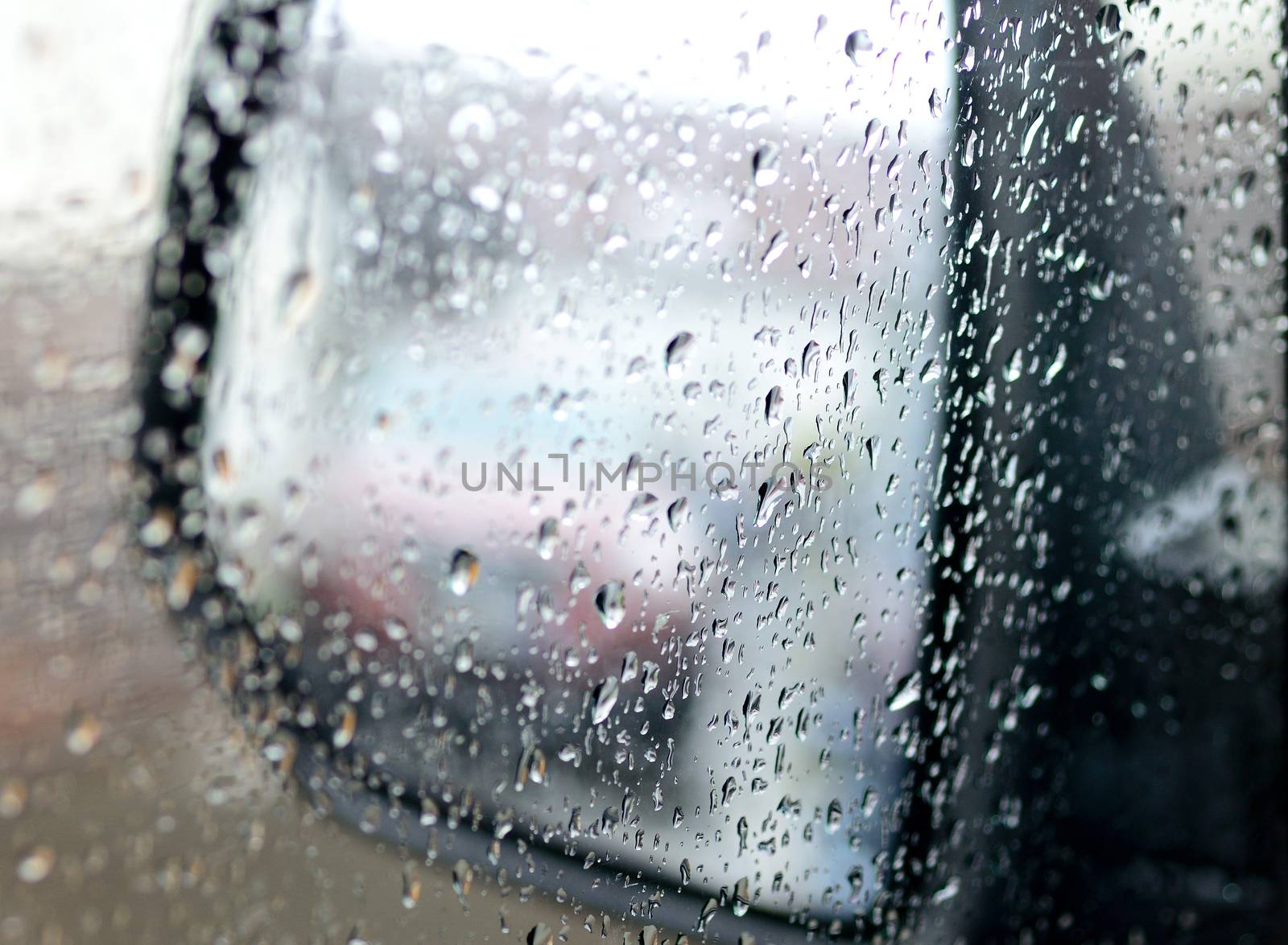 View to the rear mirror covered by water from rain.