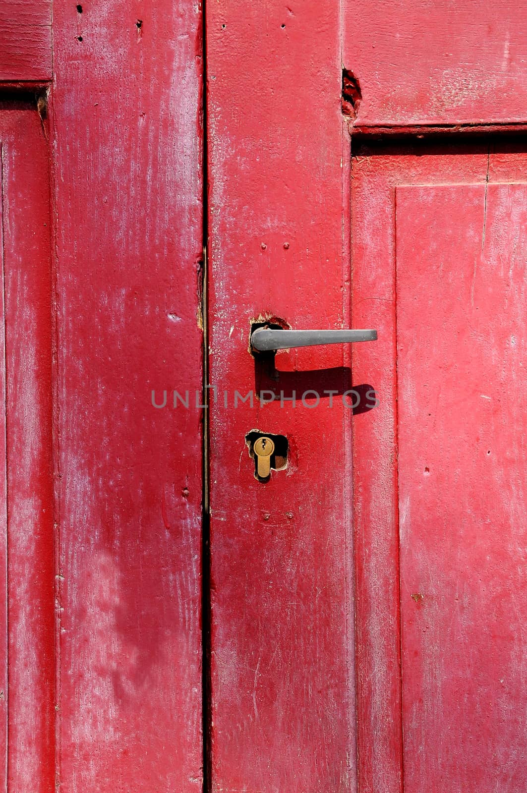 Part of old red wooden door with metal handle.