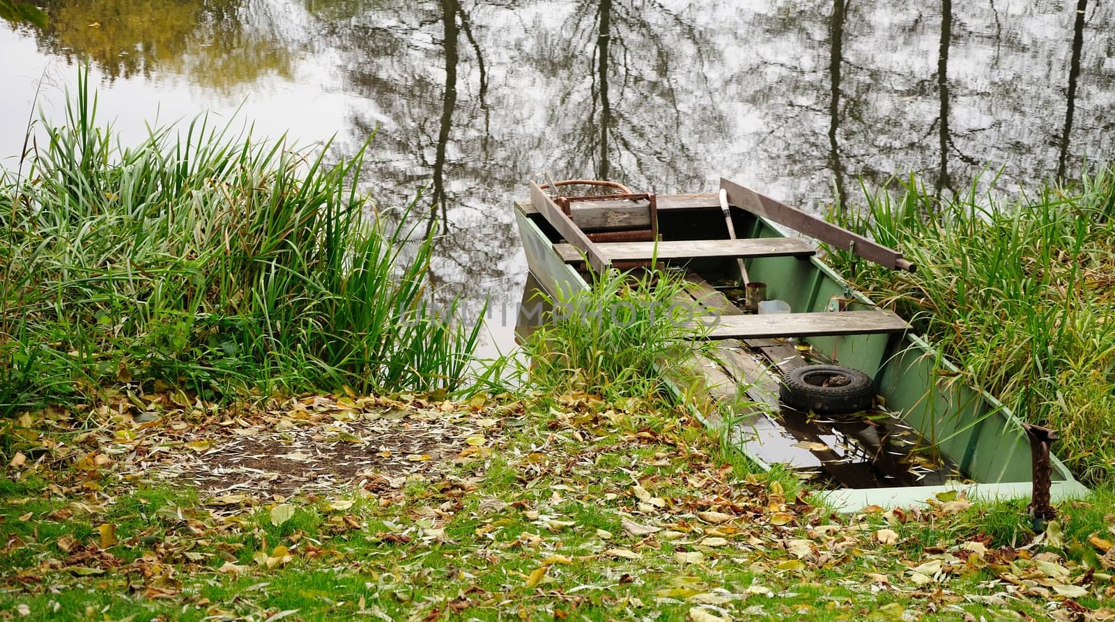 Old green wood boat anchor at riverside.