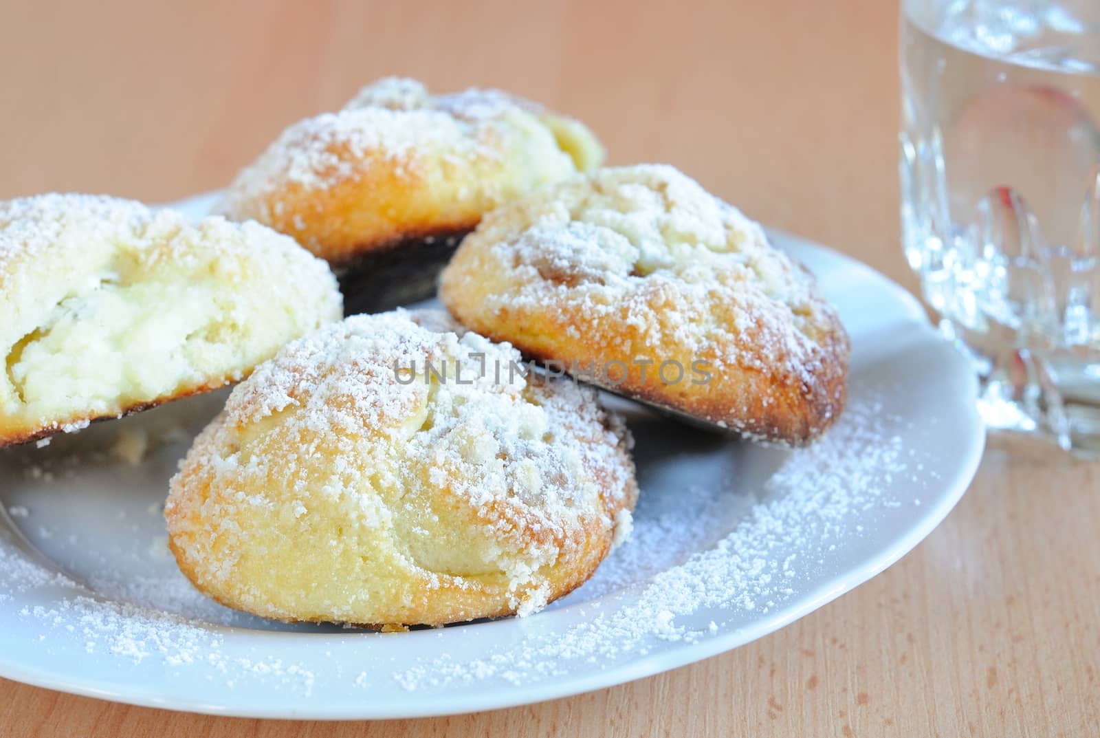 Cottage cheese cakes dredged with sugar with glass of water.