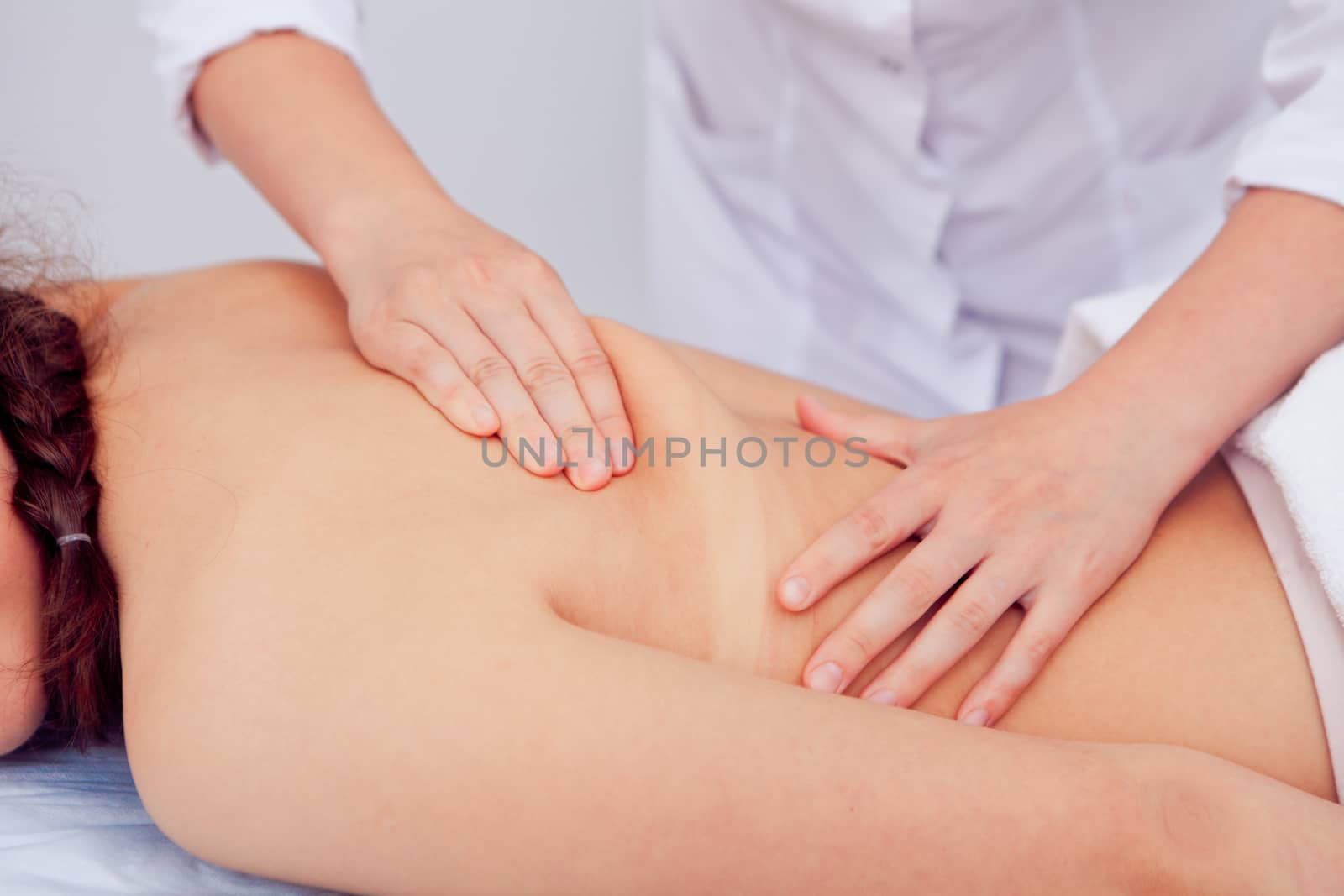 professional masseur doing massage of female back in the beauty salon.