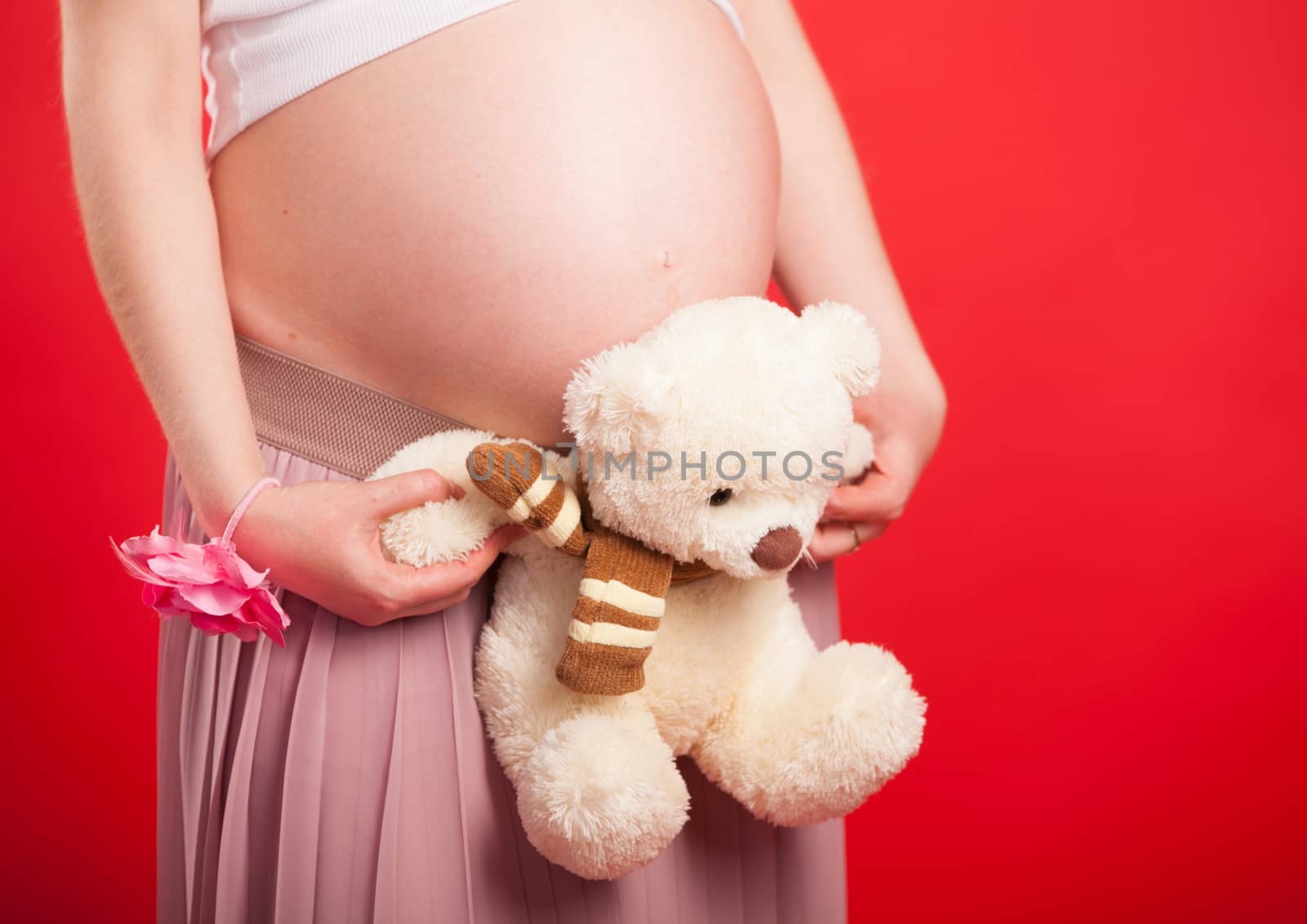 Pregnant Woman holding her hands in a heart shape on her baby bump. Pregnant Belly with fingers Heart symbol. Maternity concept. Baby Shower.