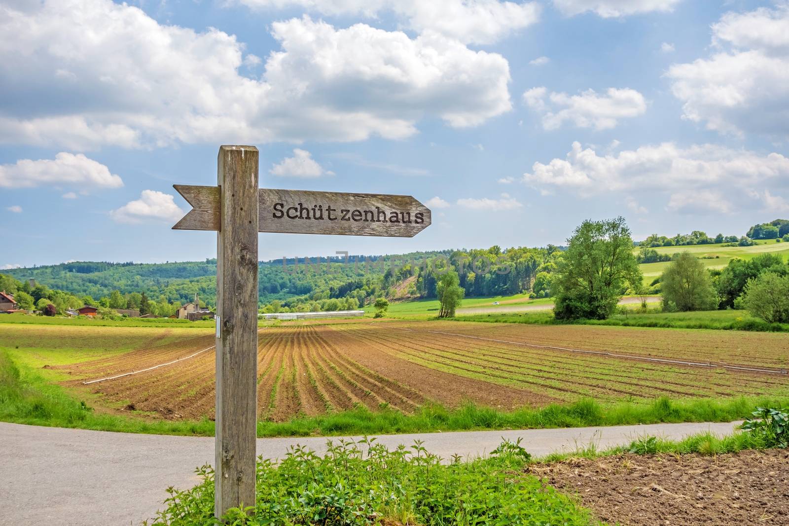 Signpost labeled with rifle associations clubhouse - in german language (Schuetzenhaus) - rural landscape in the background