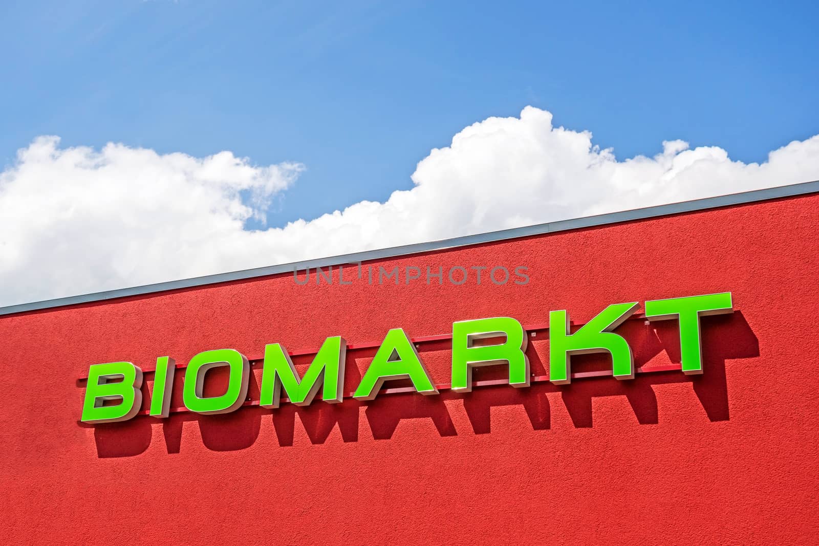Bio market red facade labeled with "BIOMARKT", german language, blue sky with clouds