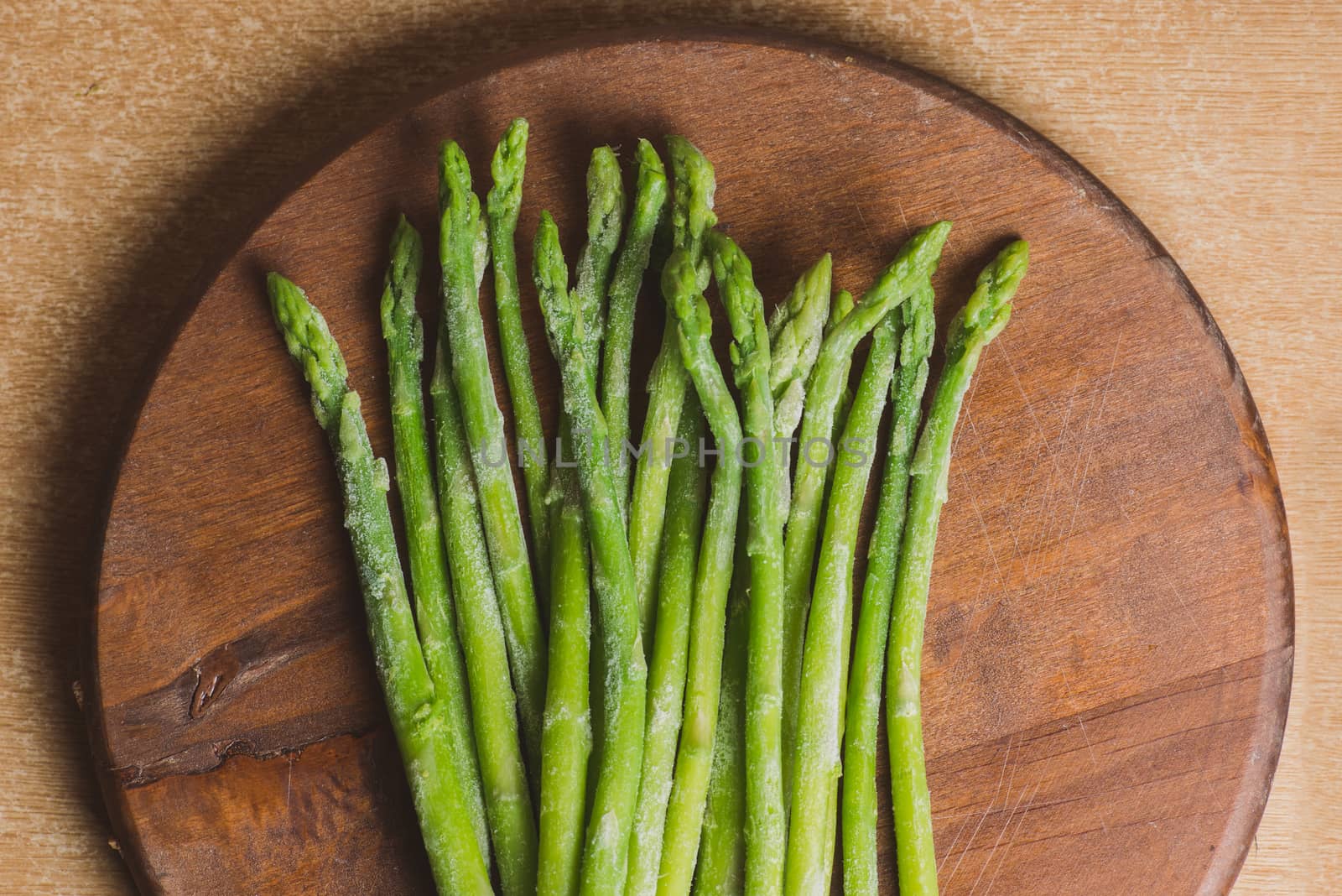 Frozen sticks of asparagus on rustic wood background. horizontal view