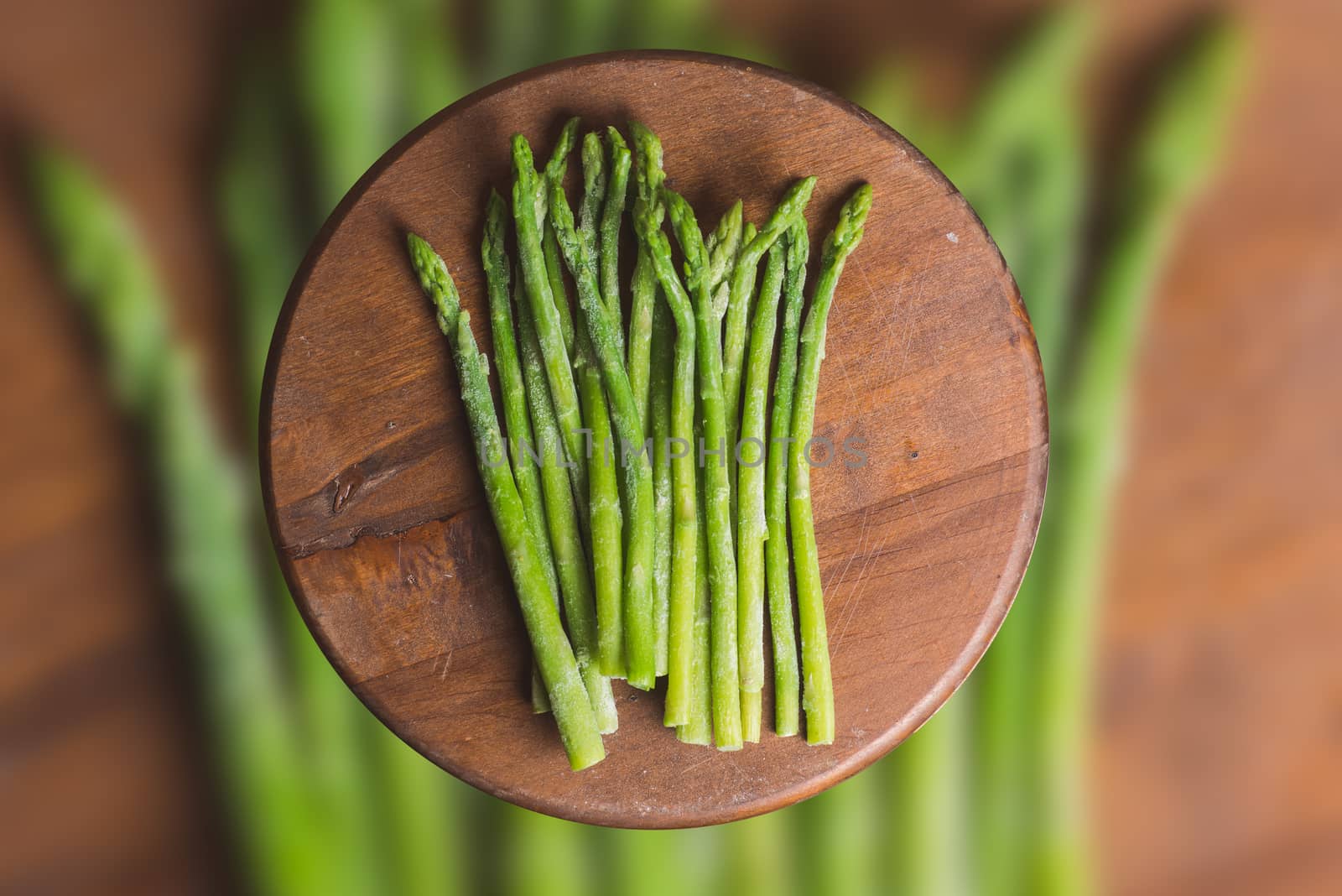 Frozen sticks of asparagus on rustic blurred wood and vegetable background. horizontal view