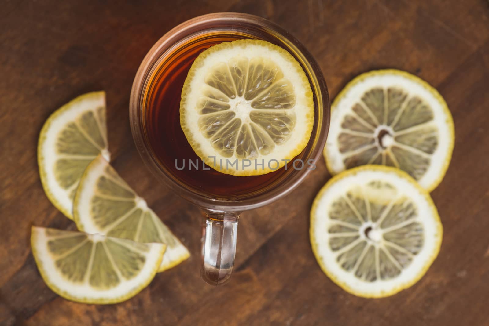 Top view of black tea with lemon in cup and on wooden plank table.