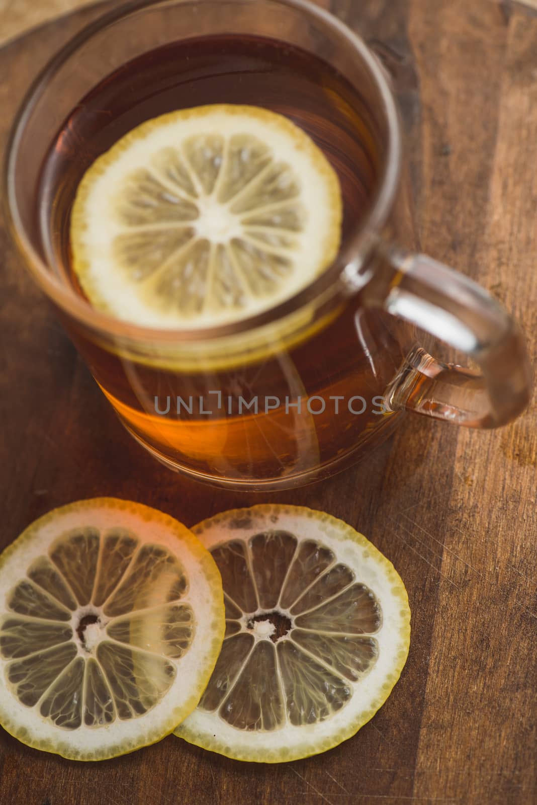 Top view of black tea with lemon in cup and on wooden plank table by skrotov