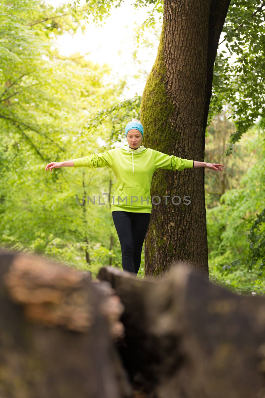 Woman holding balance on tree trunk in nature. by kasto