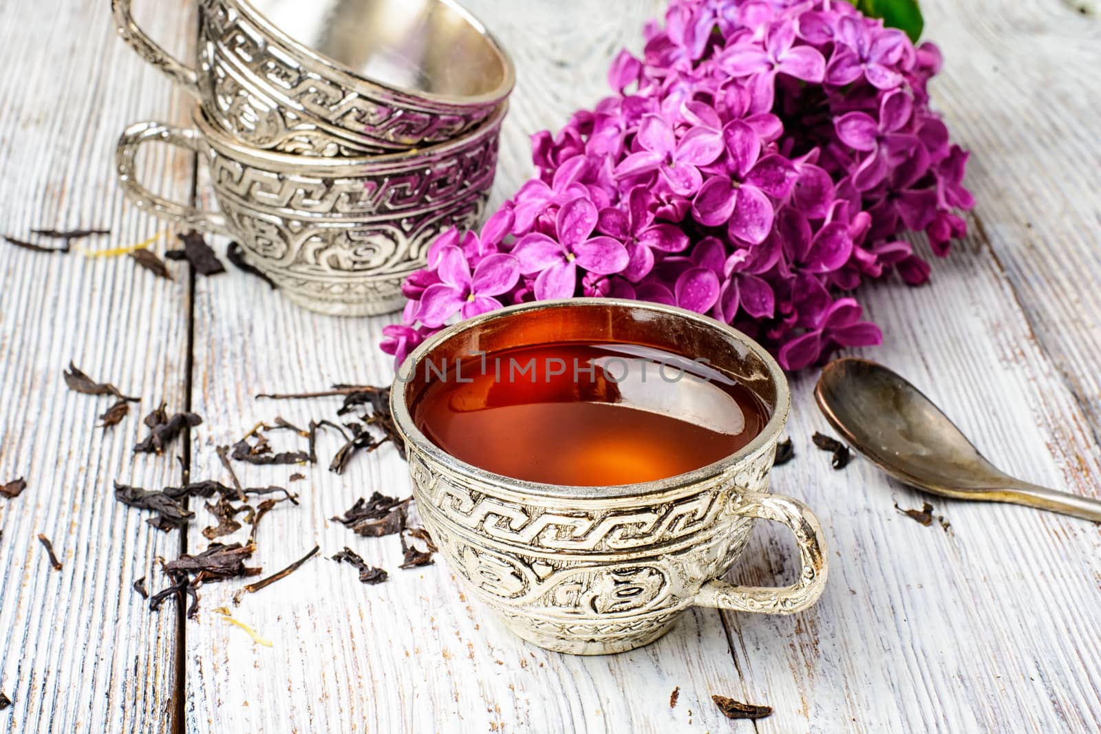 Aromatic spring tea fashion in an iron mug and a branch of a blossoming lilac