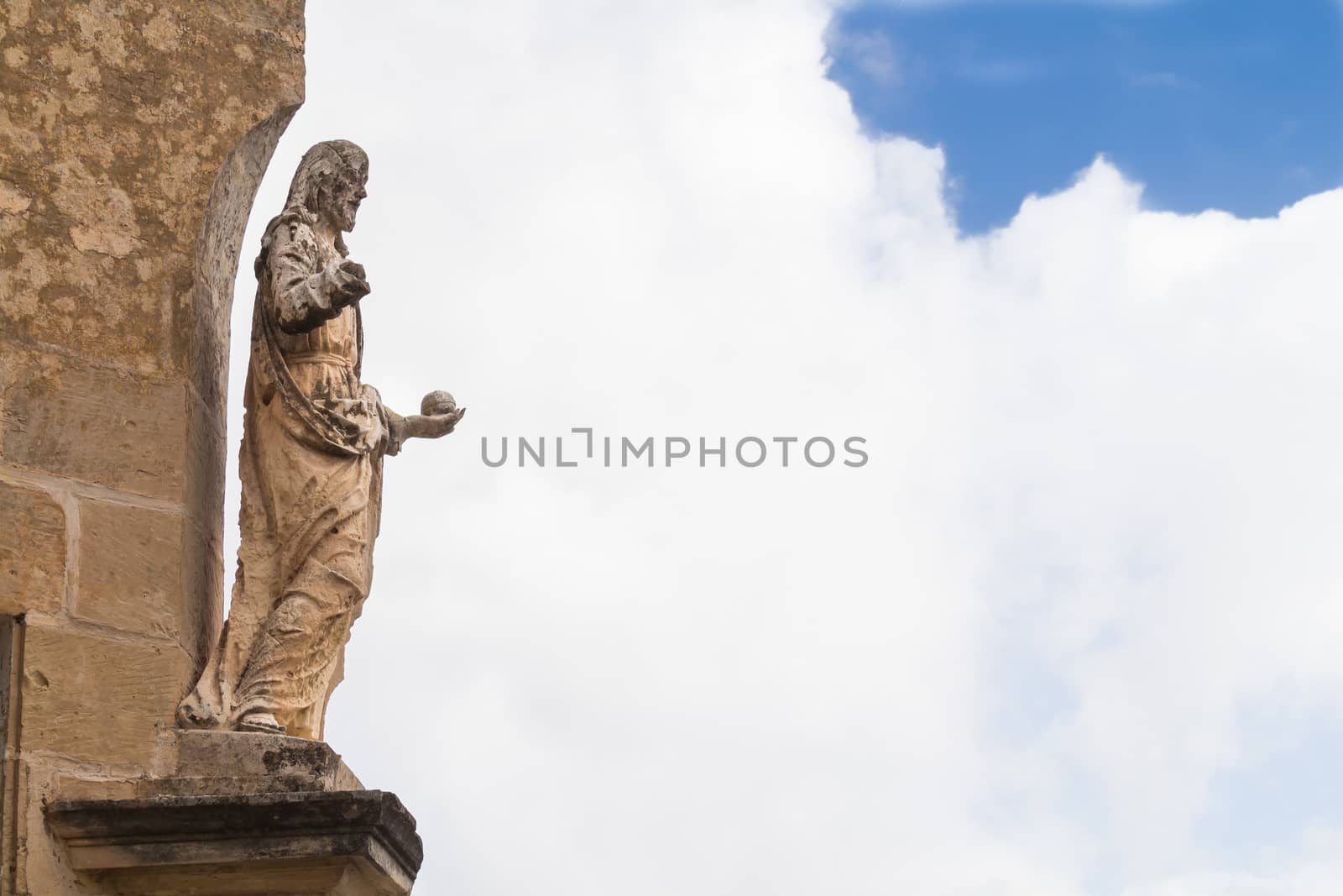 Corner of a house with a statue of a saint. Medieval fortress and former capital of Malta - Mdina. Cloudy sky in the background.