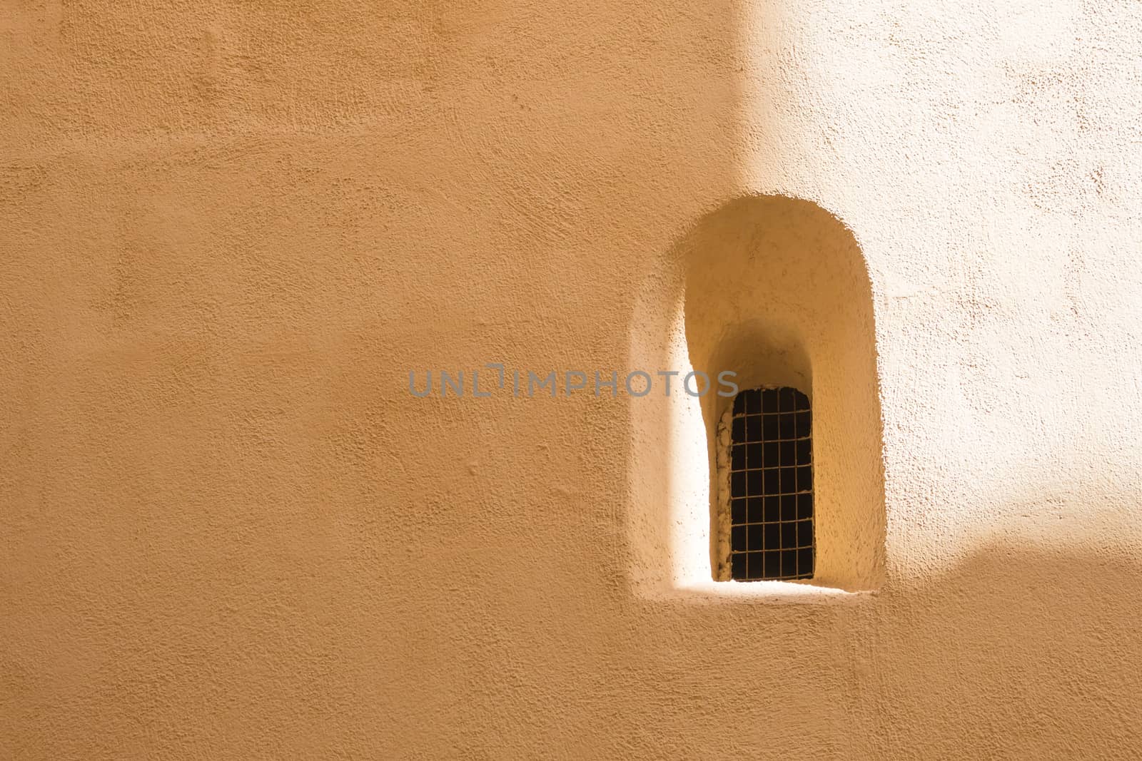 Facade of an old house with an old window with an arch in arabian style. Wall partly enlightened by the sunlight. Former capital of Malta - Mdina.