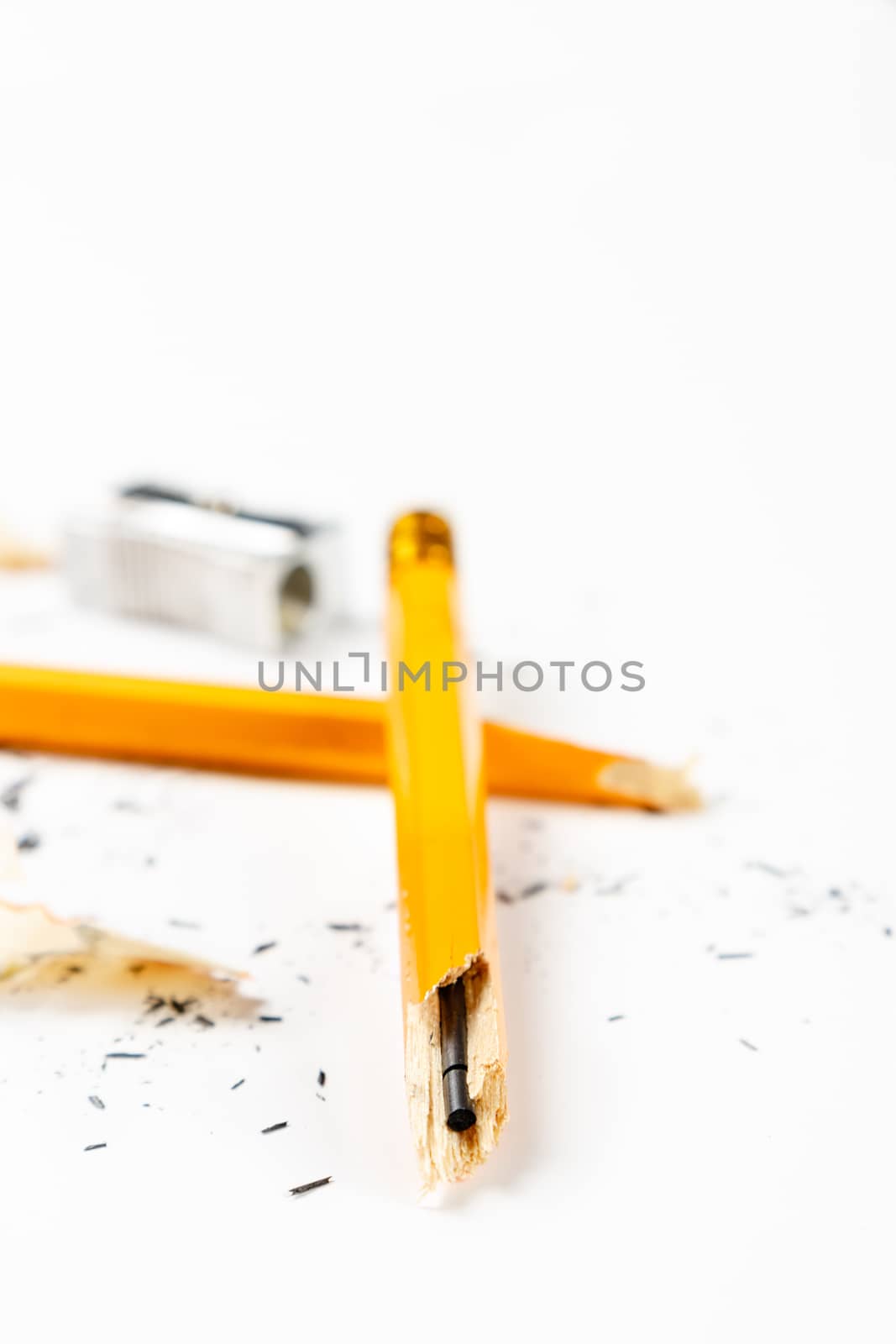 Pencil, metal sharpener and pencil shavings on white background. Vertical image.