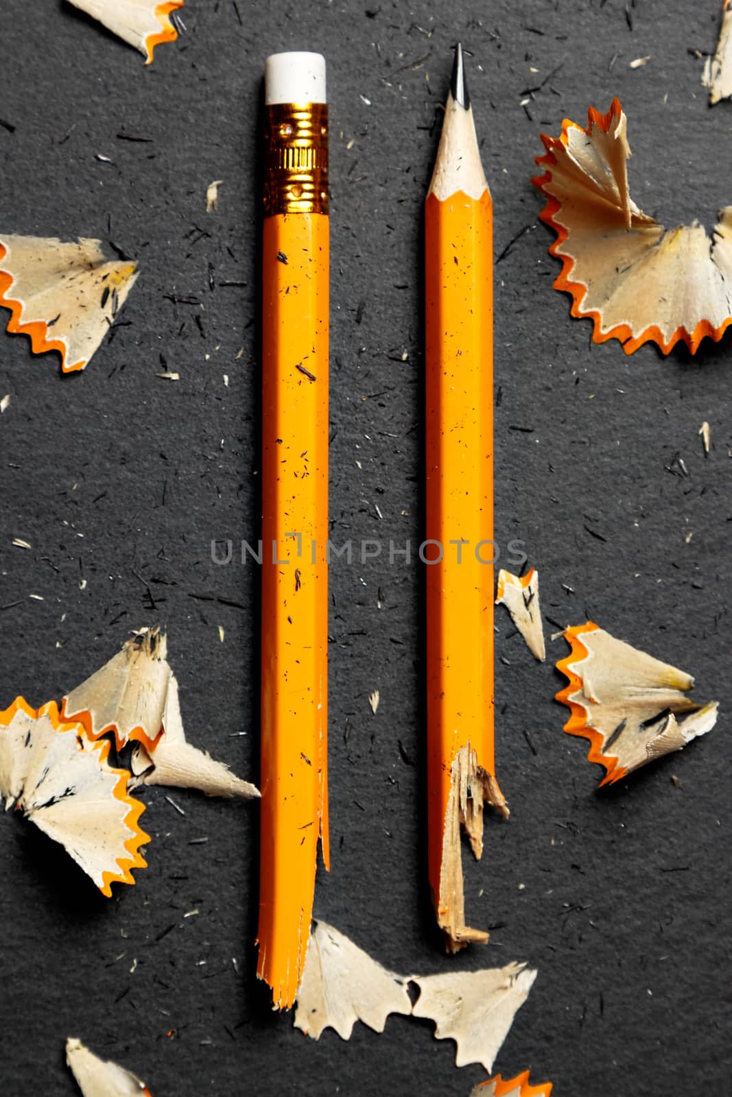 Broken pencil with shavings on black background. Vertical image.