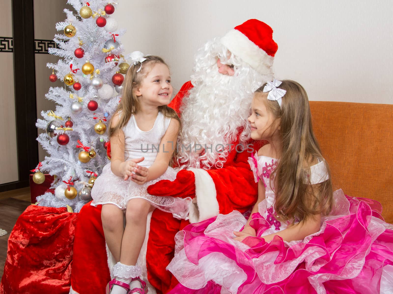 Little girl sitting on the lap of Santa Claus and tells poem by Madhourse