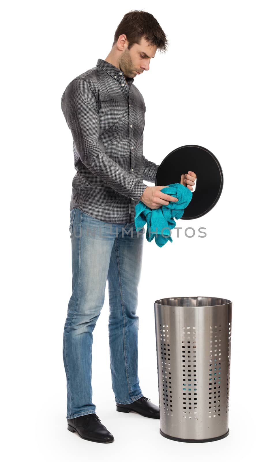 Young man putting a dirty towel in a laundry basket by michaklootwijk