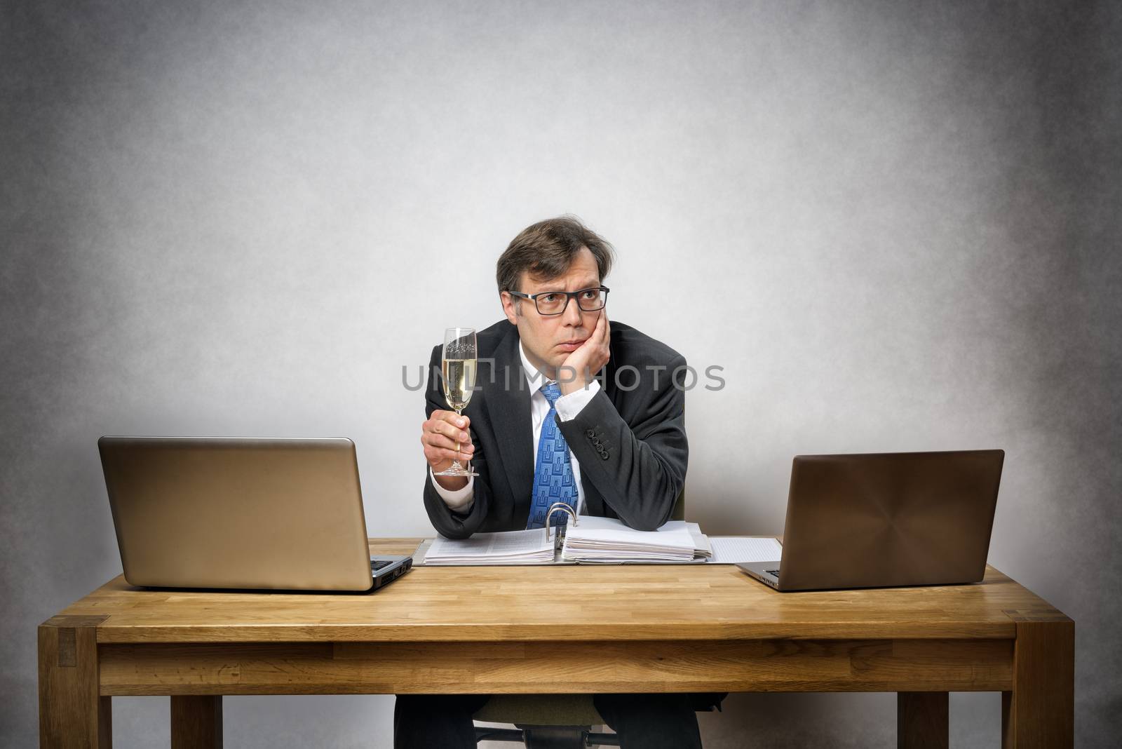 Image of frustrated lonely business man with champagne glass in office