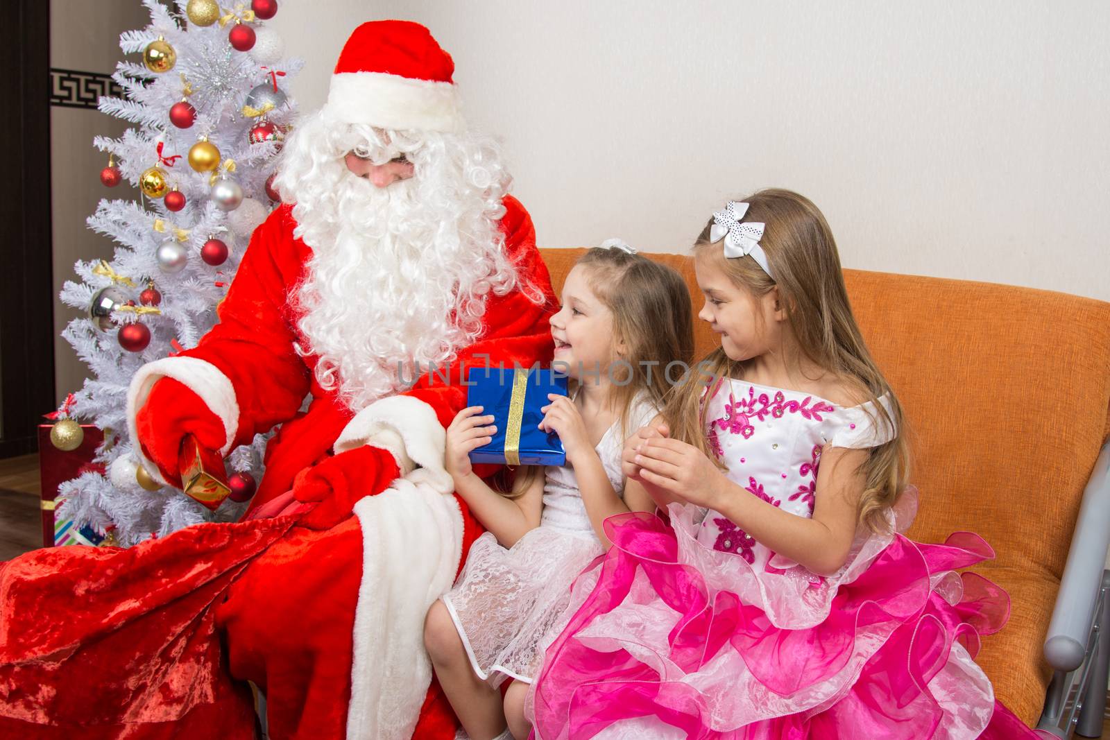 Santa Claus gets gifts from the bag and gives children