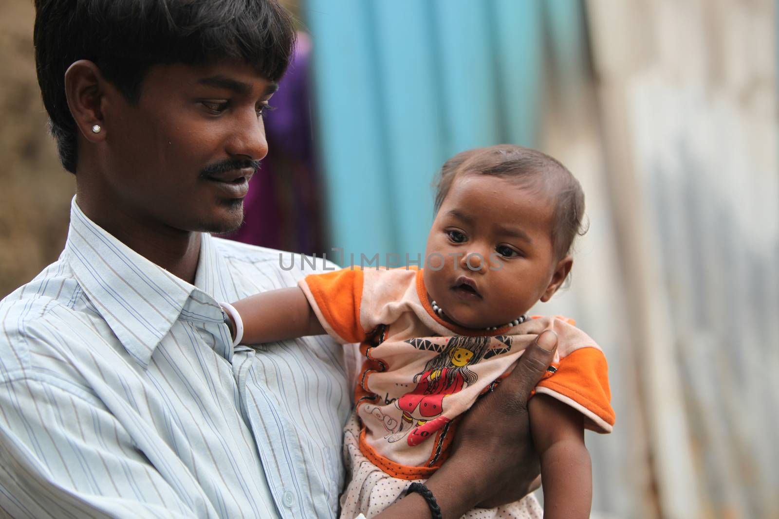 A portrait of a poor Indian father holding his little son, looking at him lovingly.