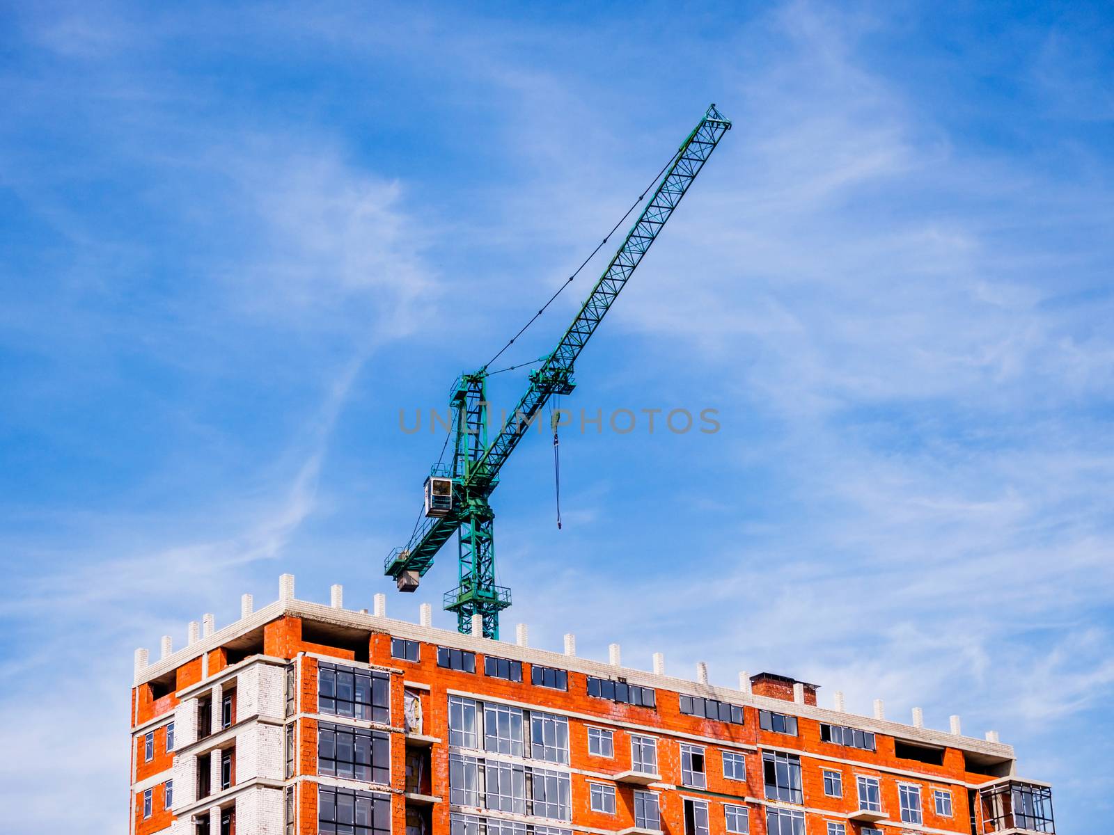 Green construction crane with amazing blue sky background