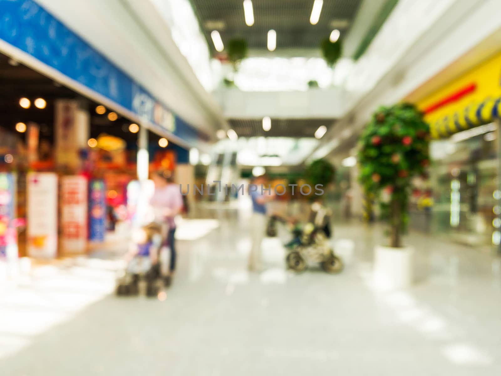 Abstract background of shopping mall with unrecognizable persons with stroller, shallow depth of focus.