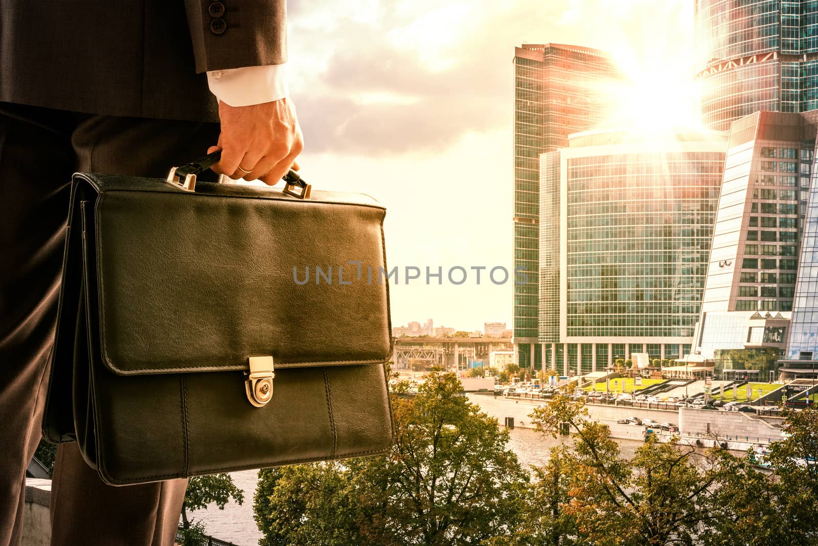 Businessman with suitcase against modern city by cherezoff