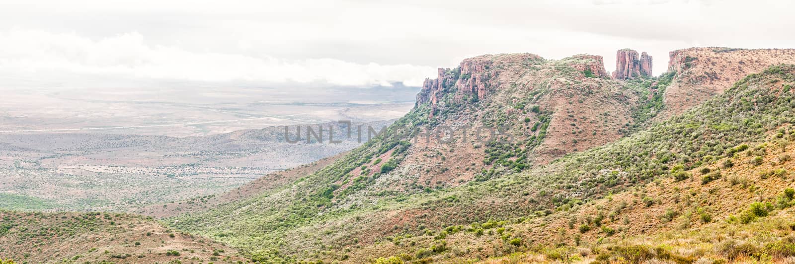 Rain is falling in a stitched panorama of dolerite columns with the Valley of Desolation below as seen from the road to viewpoint next to the columns near Graaff Reinet