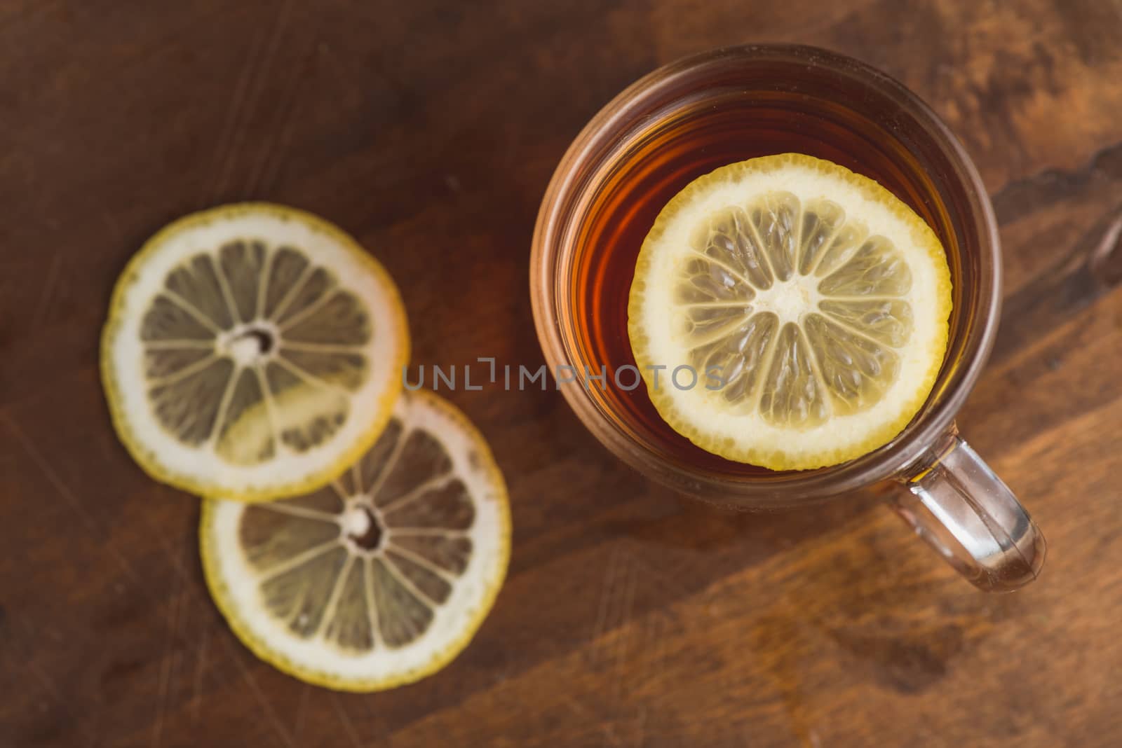 Top view of black tea with lemon in cup and on wooden plank table.