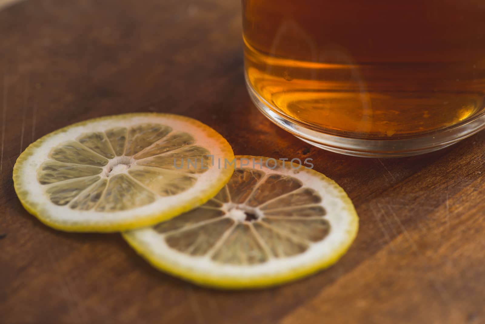 Top view of black tea with lemon in cup and on wooden plank table.