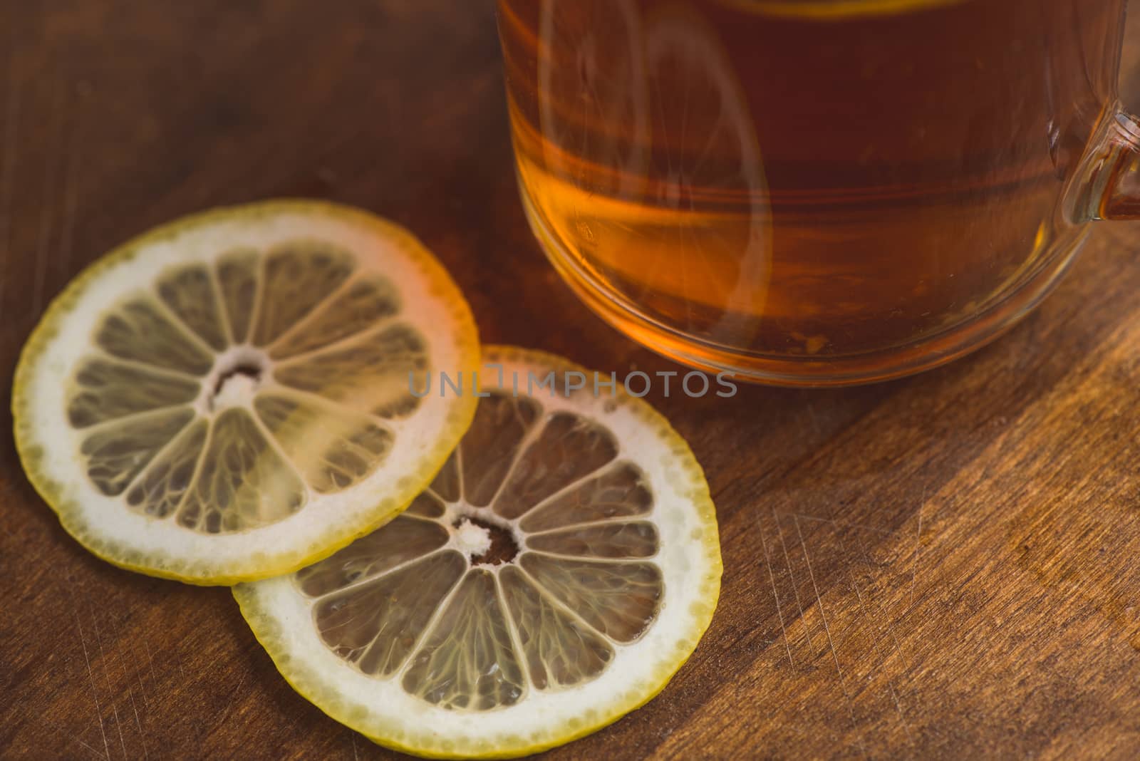 Top view of black tea with lemon in cup and on wooden plank table.