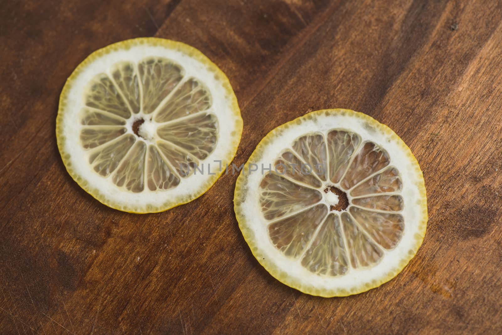 two thin slices Fresh Lemon on Wood Table Background, Rustic Style. by skrotov