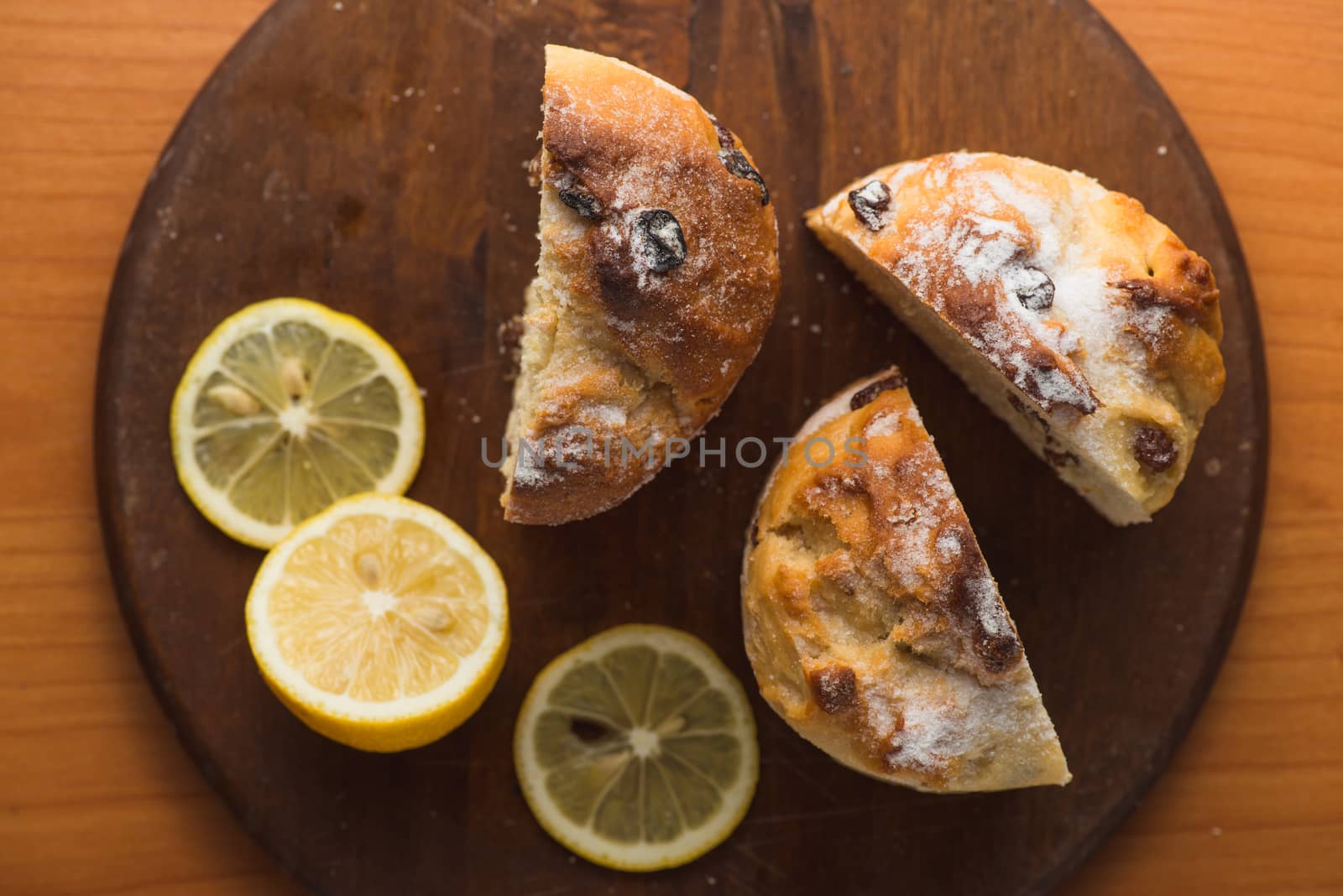 Top view of muffin with lemon in cup and on wooden plank table.