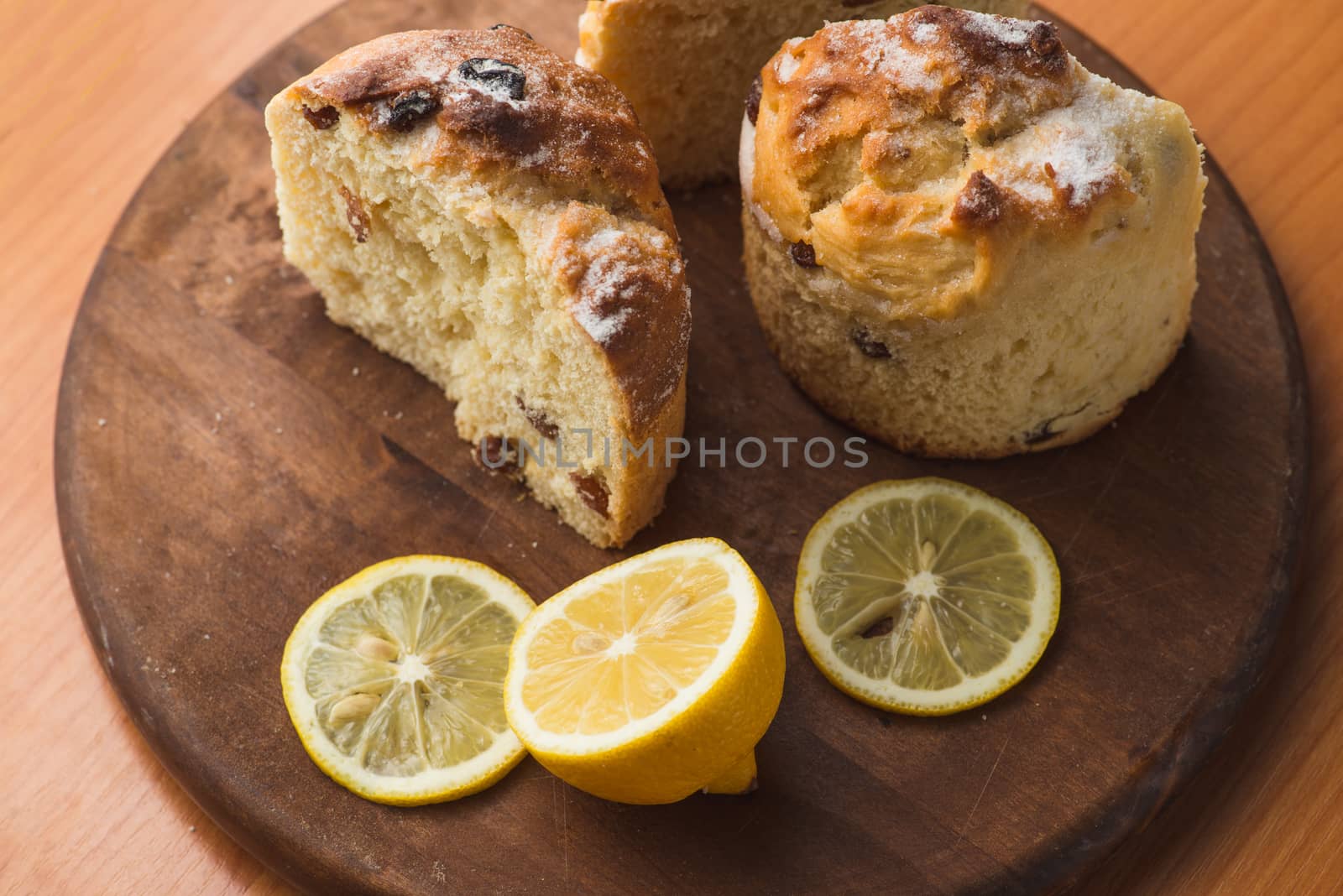 Top view of muffin with lemon in cup and on wooden plank table.