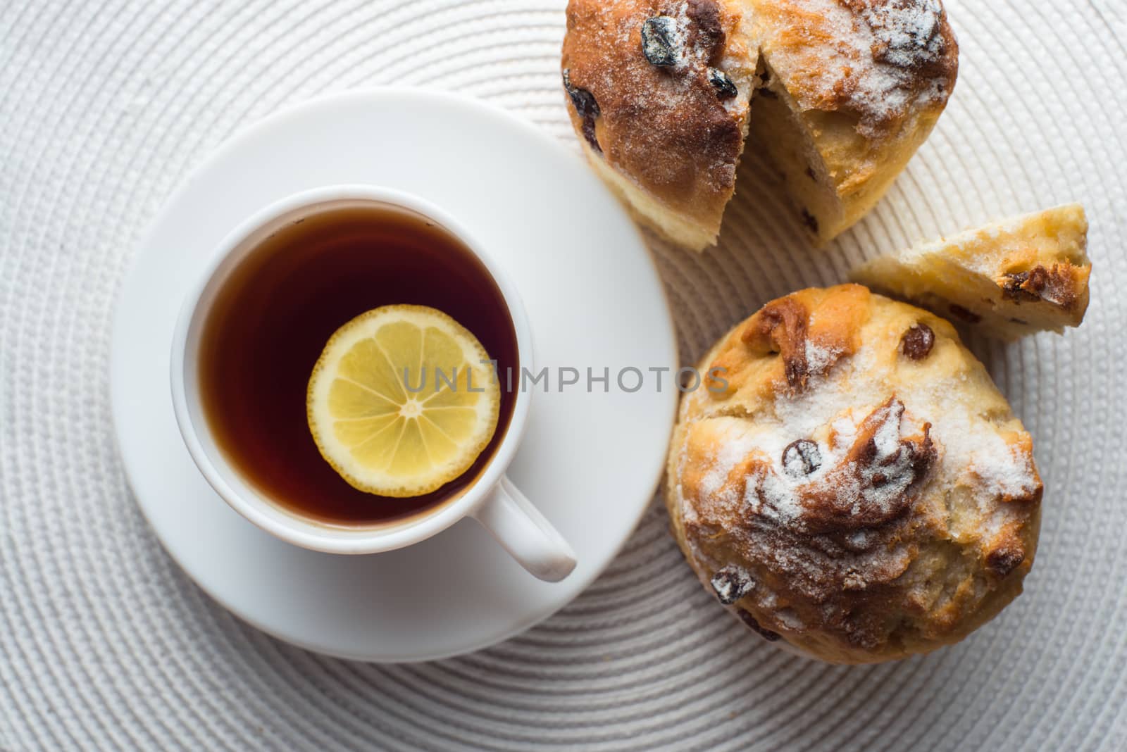 two Homemade carrot muffins with cap of tea and lemon on white fabric background. top view.