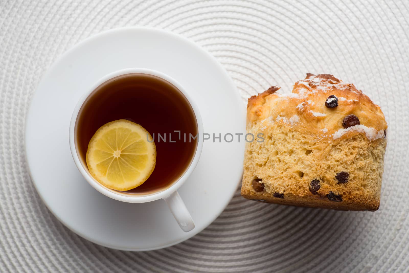 Homemade carrot muffin with cap of tea and lemon on white fabric background. top view