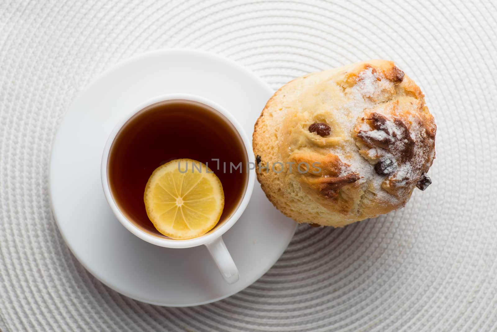 Homemade carrot muffin with cap of tea and lemon on white fabric background. top view by skrotov