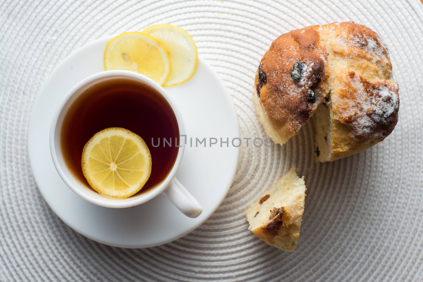 Homemade carrot muffin with cap of tea and lemon on white fabric background. top view