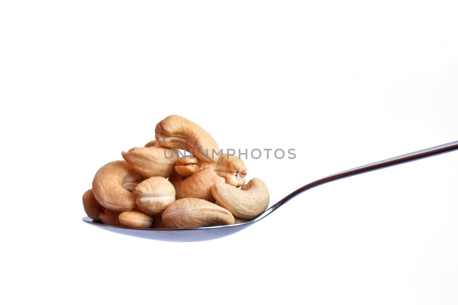 Spoonful of cashew nuts on white background by ekachailo