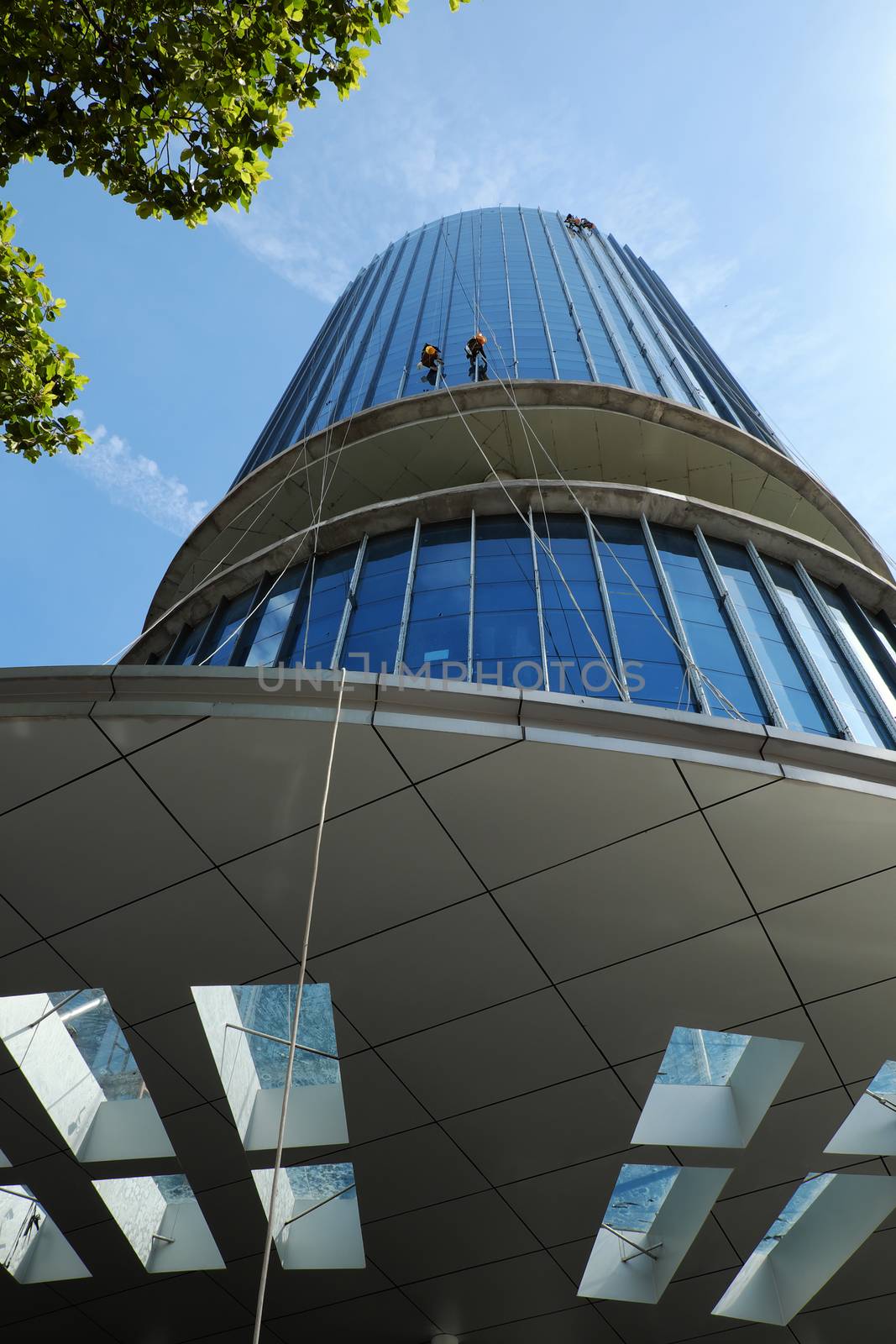 Group of Asian construction worker working on highrise building, Vietnamese man climb on rope and clean glass surface of skyscraper, a dangerous job of industry service