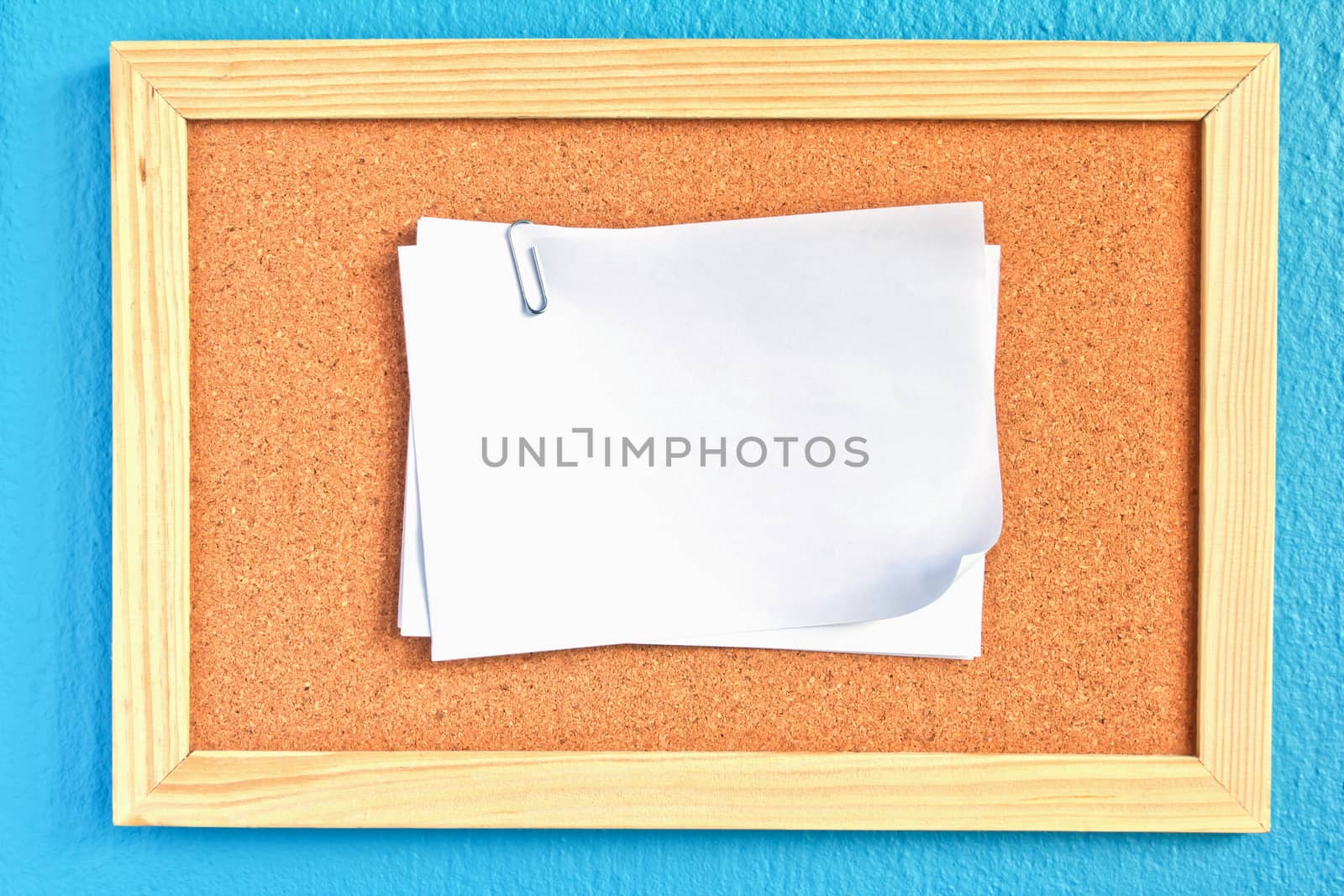 notepad on cork board on sky-blue background